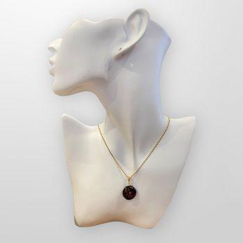 Fine round amber amulet in dark cherry colour