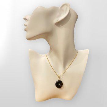 Stylish round amulet in dark amber