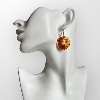 Distinctive yellowish amber earrings with bark remnants in the shape of an irregular circle with a hole