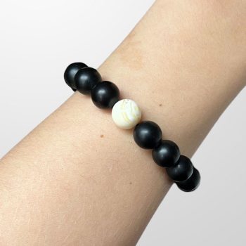 Youthful bracelet of matt black amber beads with a landscape bead in the centre