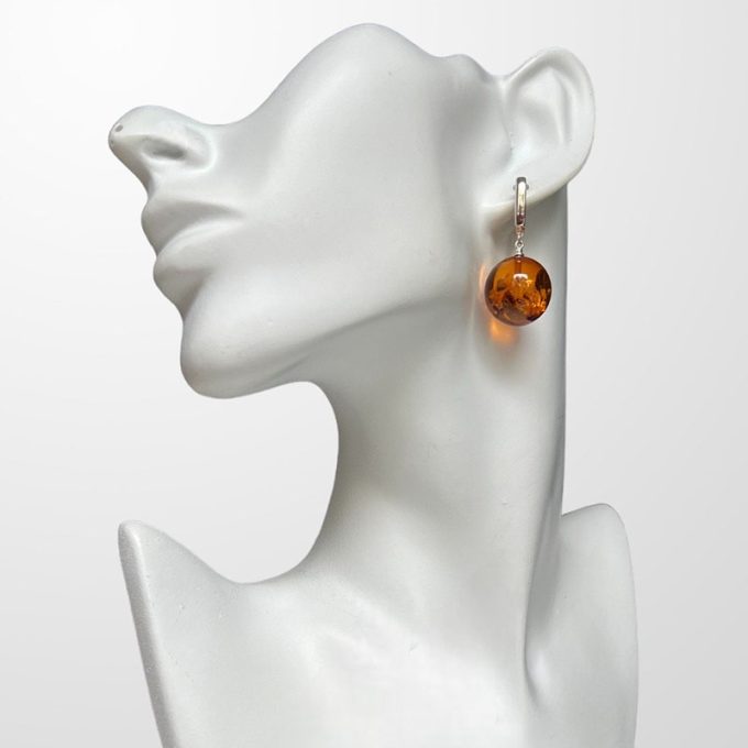 Stylish amber earrings in a smooth abstract shape in honey colour with mica