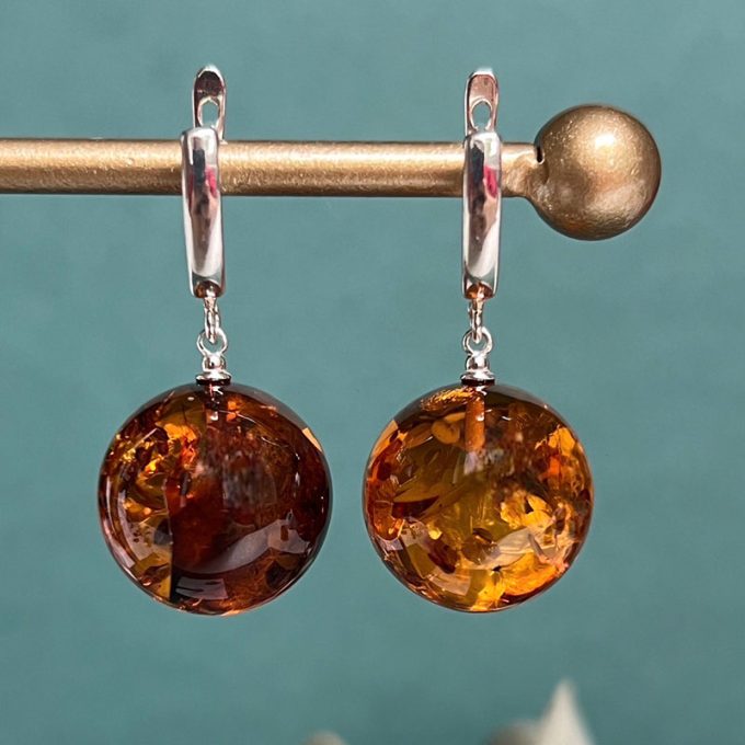 Stylish amber earrings in a smooth abstract shape in honey colour with mica
