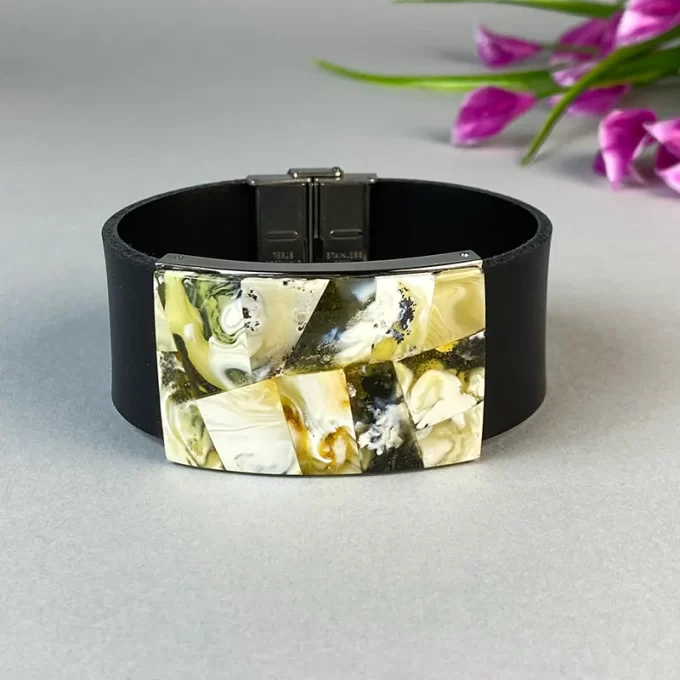 Fashionable black leather bracelet with greenish landscape amber detail