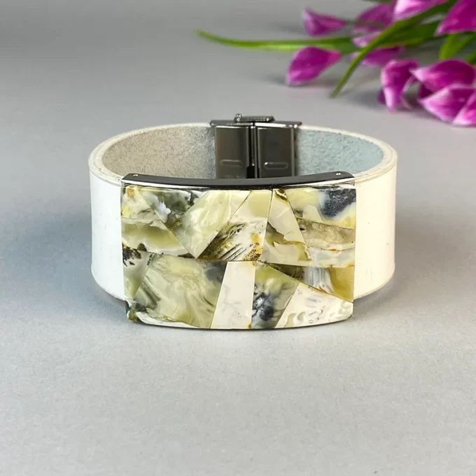 Stylish white leather bracelet with greenish landscape amber detail