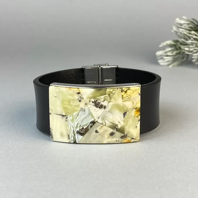 Stylish black leather bracelet with greenish landscape amber detail